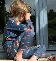 fotografia de niño mirando por la ventana, lleva puesto pijama aqua parade