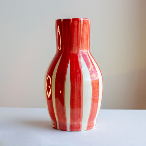 fotografia de jarra de ceramica a rayas rojas y blancas