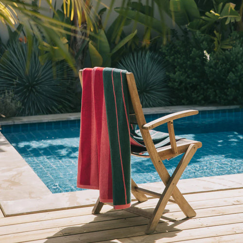 fotografia de toalla rosa con verde oscuro y rojo sobre silla de playa