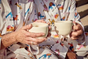 manos sujetando tazas blancas de cerámica llevando pijamas hump huddle a juego