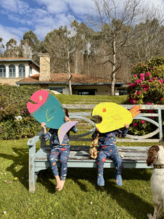 fotografia de dos niños con pijama de bebé y niño  aqua parade sentados en un banco jugando con peces de cartón