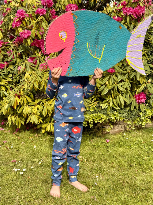 fotografía de niño jugando con pez de cartón llevando pijama de aqua parade