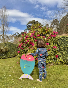 fotografía de niña de espaldas sujetando pece de cartón llevando pijama aqua parade