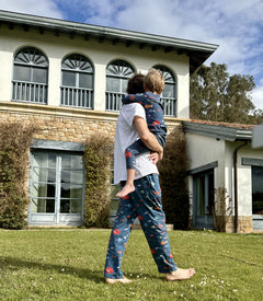 fotografía de padre con su hijo con pijamas aqua parade a juego cargando a su hijo frente a una casa